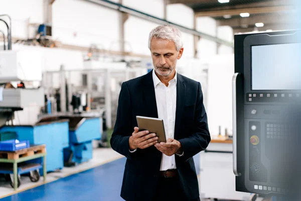 Ejecutivo con tableta en planta industrial